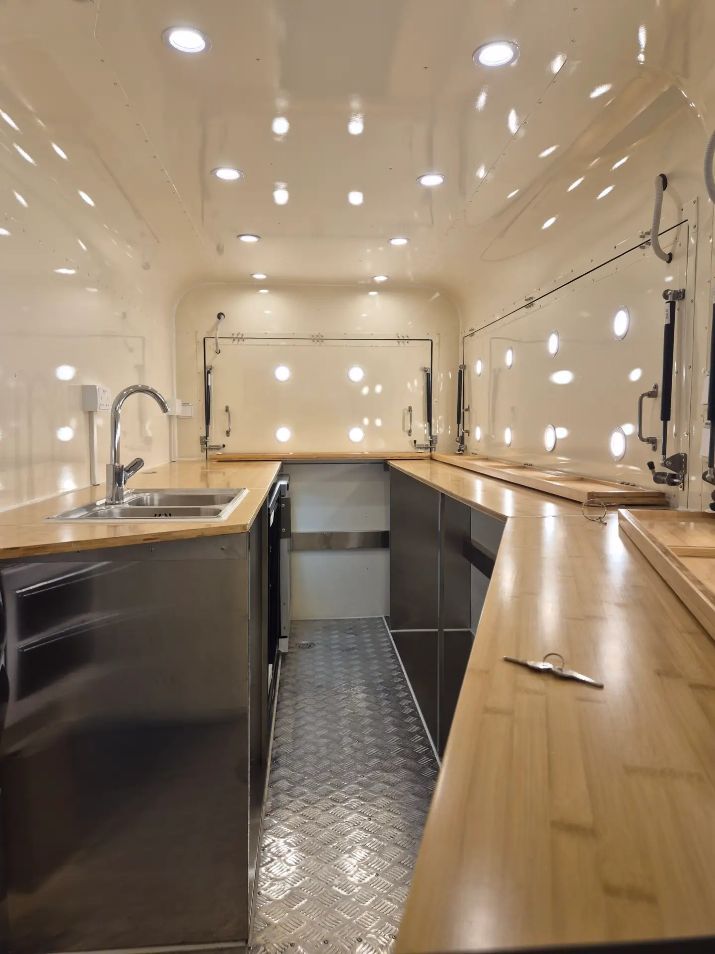 Interior view of the food van showing professional workspace with wooden countertops and chrome fixtures
